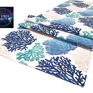 Peut inclure: Un chemin de table blanc avec un motif de récif corallien bleu et turquoise. Le chemin de table est plié en deux et a un fond blanc avec des branches de corail bleues et turquoise.