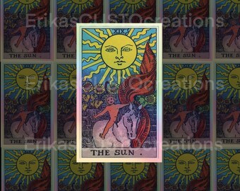 Puede incluir: Una carta del tarot que representa El Sol, la 19ª carta de los Arcanos Mayores. La carta presenta un sol amarillo brillante con una cara humana, que irradia rayos de luz. Un niño desnudo monta un caballo blanco, con una bandera roja ondeando detrás de él. La carta está rodeada por un borde azul y verde con un marco dorado.