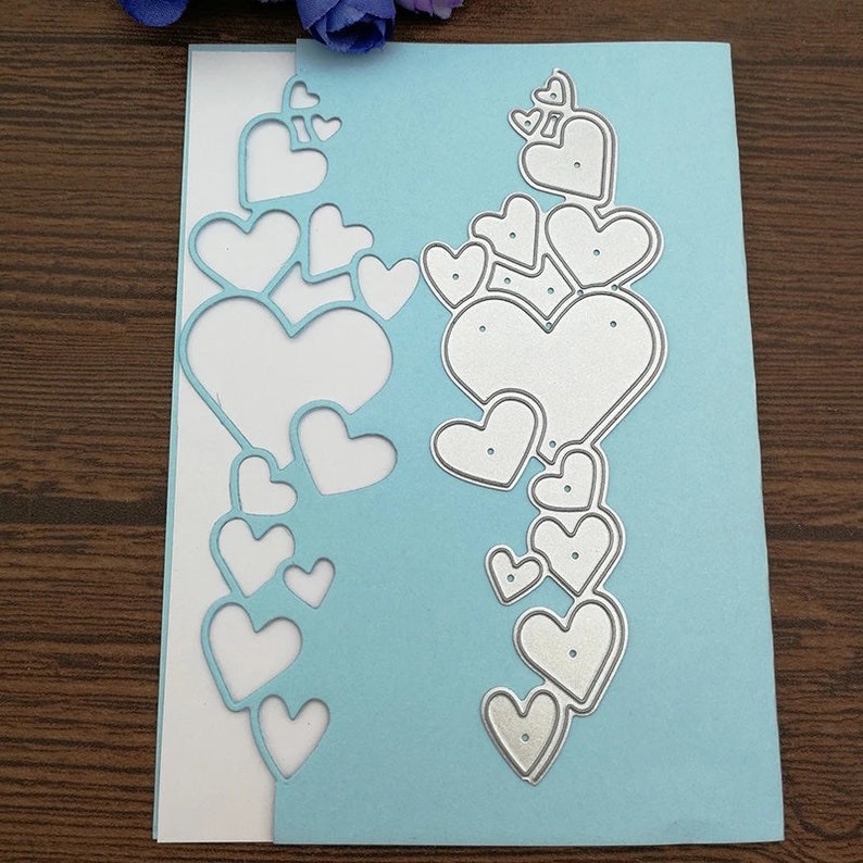 Puede incluir: Una tarjeta azul claro con una inserci&oacute;n blanca, con un dise&ntilde;o troquelado de corazones en cascada. Los corazones troquelados son de varios tama&ntilde;os, creando un efecto en capas. Adecuado para proyectos de manualidades y scrapbooking.