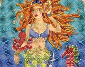 May include: A needlepoint design featuring a mermaid with long red hair, a yellow and green tail, and a blue seashell bra. The mermaid is surrounded by sea life, including a seahorse, a starfish, and seaweed.