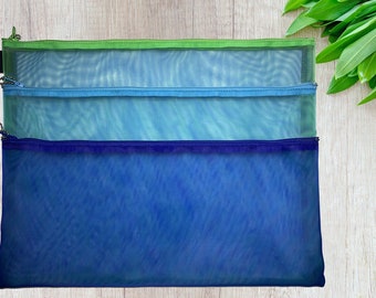 May include: Three mesh zippered pouches in shades of blue and green. The pouches are stacked on top of each other, with the largest pouch at the bottom and the smallest pouch at the top.