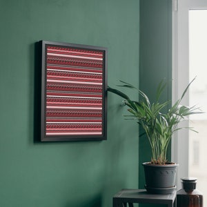 May include: A framed print with a red, white, and black geometric pattern hangs on a green wall. A potted plant sits on a gray table next to a brown glass bottle.