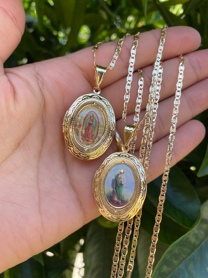 Puede incluir: Dos medallones ovalados de oro en una cadena de oro. Los medallones presentan im&aacute;genes religiosas. Un medall&oacute;n tiene una imagen de la Virgen Mar&iacute;a y el otro tiene una imagen de un santo.