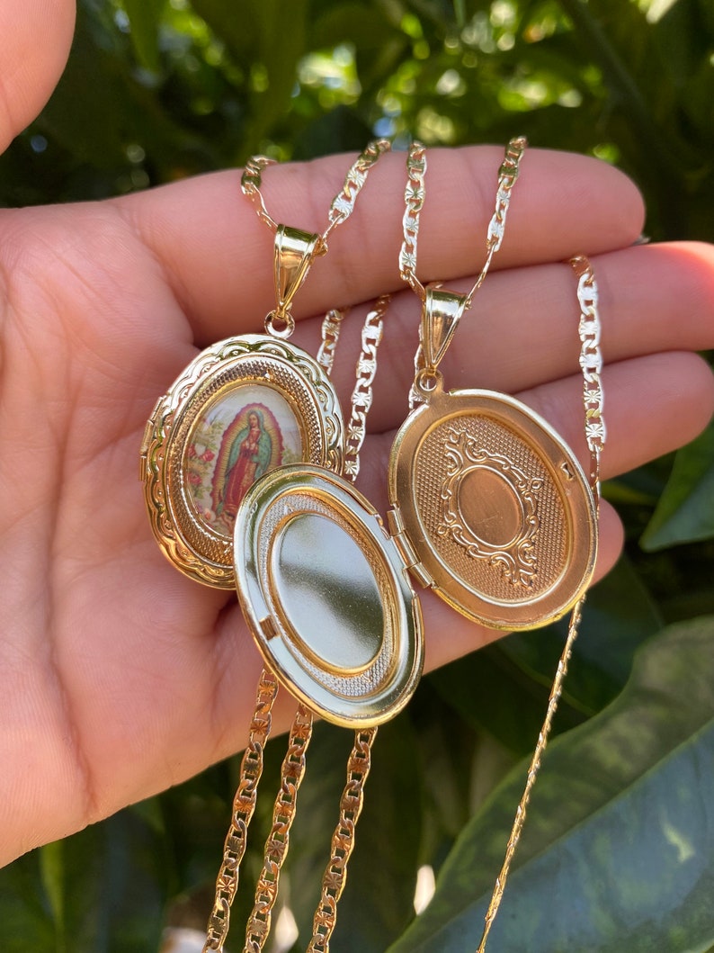 Puede incluir: Dos collares con medallones ovalados de oro y cadenas. Un medall&oacute;n presenta una imagen religiosa de la Virgen Mar&iacute;a. El otro medall&oacute;n tiene un dise&ntilde;o decorativo.