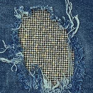 May include: A close-up of a denim fabric with a hole that has been patched with a sparkly, iridescent material. The patch is a grid of small, round, shiny objects.