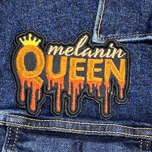 May include: A black and orange embroidered patch with the words "melanin queen" in a dripping font. The patch has a gold crown above the word "queen".