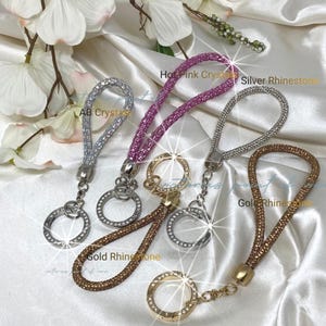 Puede incluir: Cuatro llaveros de muñeca con bucles incrustados de pedrería y anillos metálicos circulares. Los colores incluyen cristales AB, cristales rosa intenso, pedrería plateada y pedrería dorada. Cada llavero tiene un conector de metal.