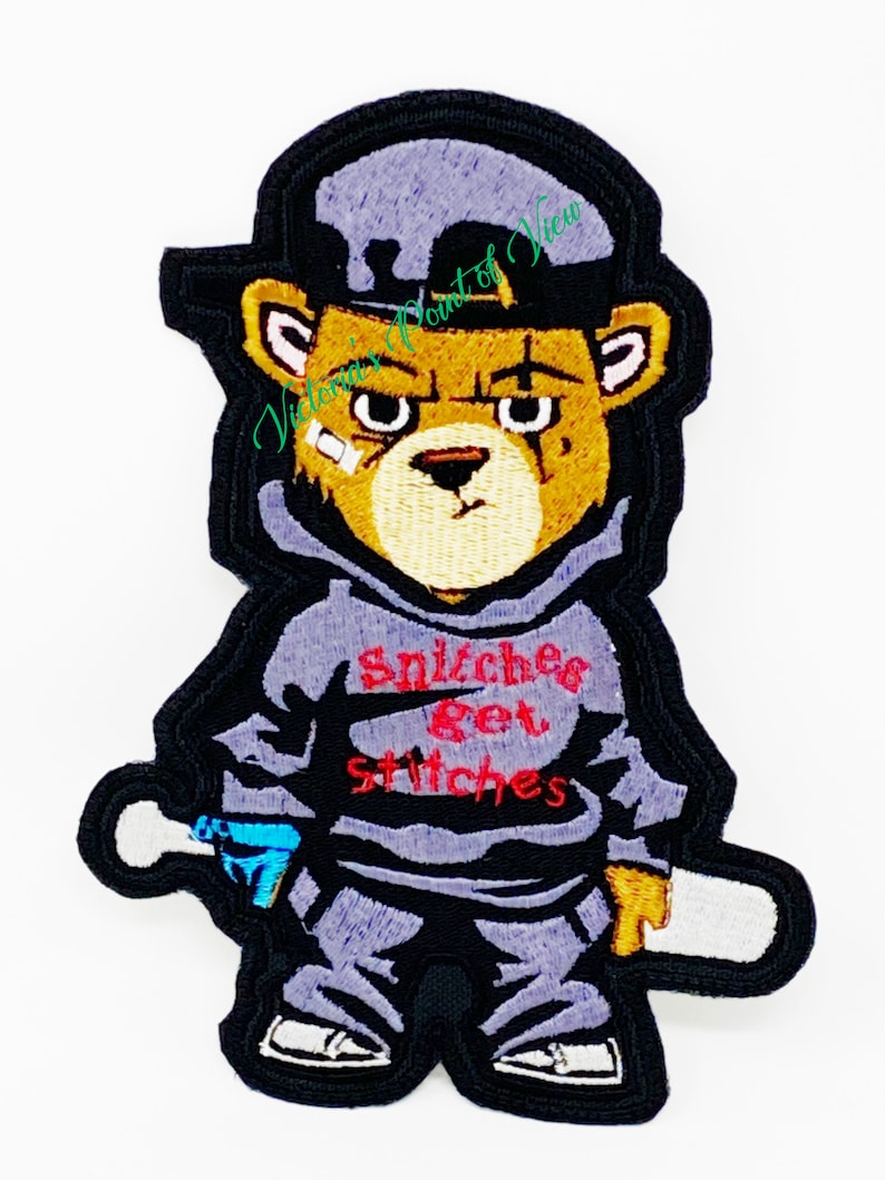Puede incluir: Un parche bordado para planchar que presenta un oso de dibujos animados con una sudadera gris, pantalones negros, una gorra de b&eacute;isbol negra y sosteniendo un bate de b&eacute;isbol blanco. El oso tiene una expresi&oacute;n gru&ntilde;ona y la sudadera tiene el texto "Snitchers Get Stitches" en rojo.