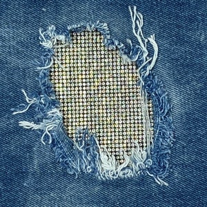 May include: A close-up of a denim fabric with a hole that has been patched with a grid of rhinestones.