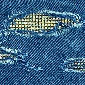 May include: Blue denim fabric with three ripped holes decorated with rows of silver rhinestones.