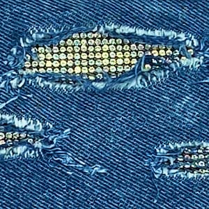 May include: Blue denim fabric with three ripped holes decorated with rows of silver rhinestones.