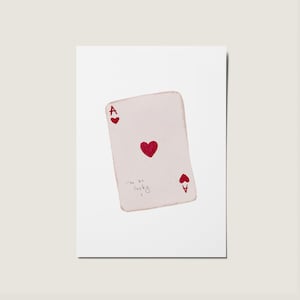 May include: A white playing card with a red ace of hearts symbol and the text "I'm so lucky" written on it.