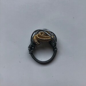 May include: A silver and gold wire ring with a spiral design.