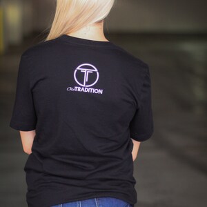 Puede incluir: Una camiseta negra con un logotipo circular blanco con la letra "T" y el texto "Old Tradition".
