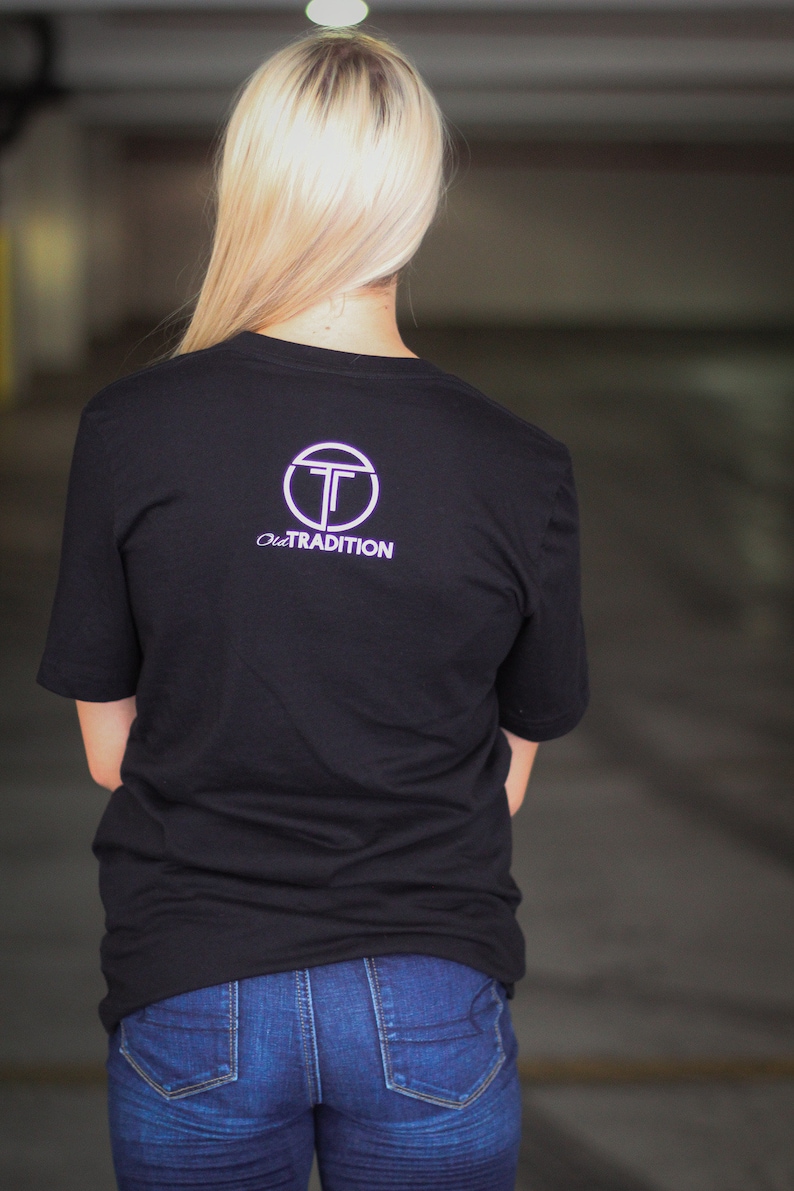 Puede incluir: Una camiseta negra con un logotipo circular blanco con la letra "T" y el texto "Old Tradition".