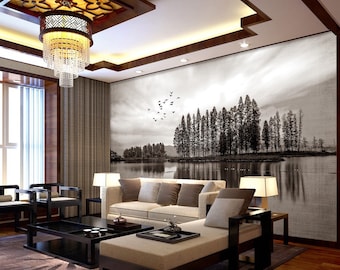 May include: A black and white photo of a lake with trees on a small island in the middle. The photo is printed on a canvas and hung on a wall in a living room. The room has a couch, a coffee table, and a lamp.