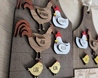 May include: A wooden Christmas ornament shaped like a cutting board with a chicken family theme. The ornament features the names "Grandpa", "Grandma", "Rob", "Keisa", "Lou", and "Kon" along with the text "The Carter Coop" and "2024".