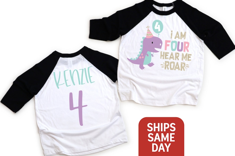 May include: White and black baseball tee shirt with a purple dinosaur graphic and the text "I am four hear me roar". The back of the shirt has the name "Kenzie" and the number "4" in purple.