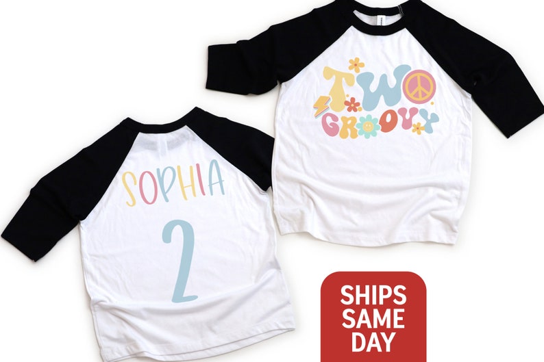 May include: White and black raglan style shirt with the words "TWO GROOVY" in pastel colors and a peace sign. The back of the shirt has the name "SOPHIA" and the number "2" in pastel colors. A fun birthday shirt.
