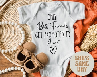 May include: White baby onesie with black text that reads "Only Best Friends Get Promoted To Aunt" with a heart underneath.