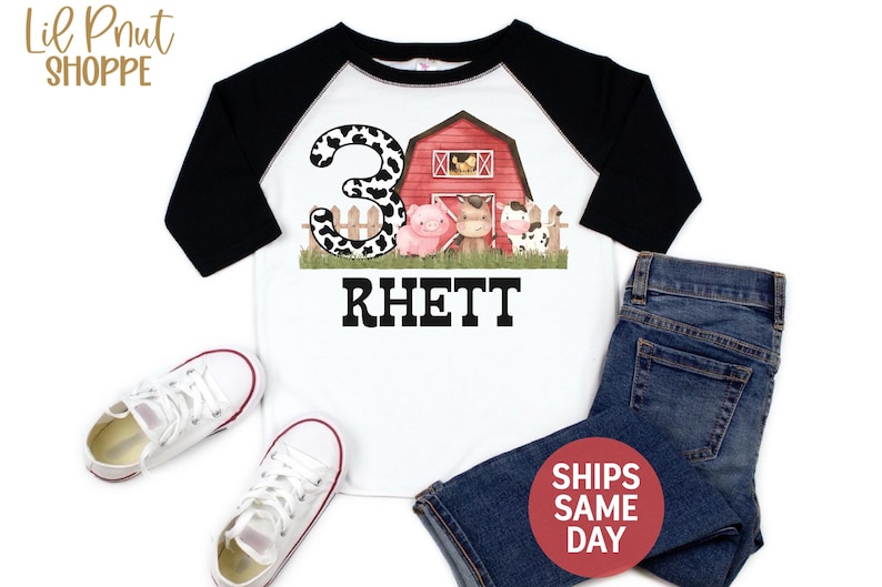 May include: A white and black raglan t-shirt with a red barn, a pig, a cow, and a horse. The number 3 is in the background with a cow print design. The name Rhett is printed below the farm scene.