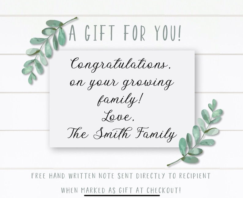 May include: A white card with a handwritten message that reads "A GIFT FOR YOU! Congratulations, on your growing family! Love. The Smith Family". The card is surrounded by green leafy branches.