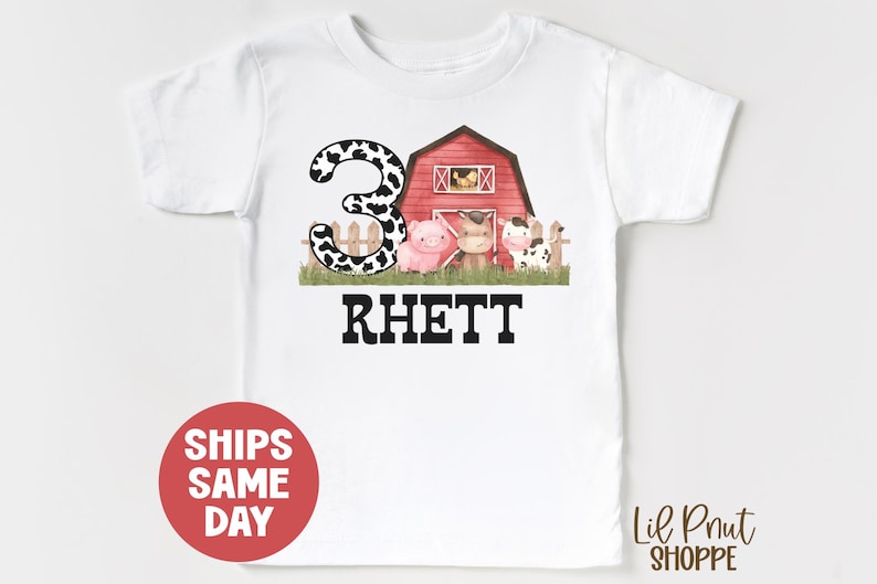 May include: White t-shirt with a black and white cow print number 3, a red barn with a pig and cow inside, and the name "Rhett" in black text.