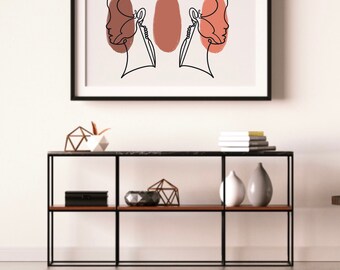 May include: A black framed print with a line drawing of two faces with a brown and orange abstract shape in the center.