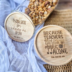 May include: Two wooden coasters with engraved messages. The first coaster says "Thank you for helping me grow" and the second coaster says "Because teachers can't live on apples alone".