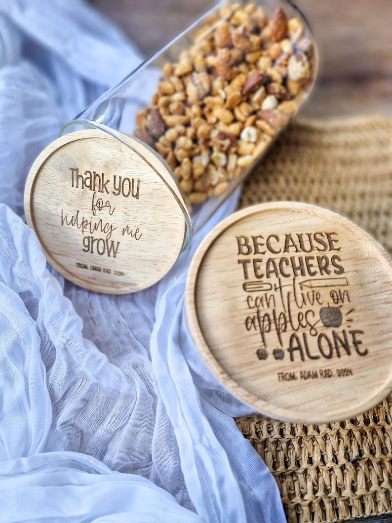 May include: Two wooden coasters with engraved messages. The first coaster says "Thank you for helping me grow" and the second coaster says "Because teachers can't live on apples alone".