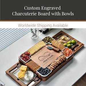 a custom engraved charcuterie board with bowls, showcasing a variety of food items such as crackers, cheese, grapes, olives, and other appetizers. The board is accompanied by a knife and a bowl, and the text "Custom Engraved Charcuterie Board with Bowls" and "Worldwide Shipping Available" are displayed above the board.