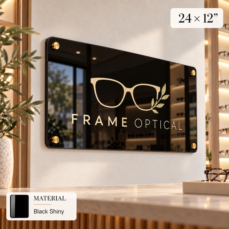 a black sign with the text "FRAME OPTICAL" and a gold-colored eye design, mounted on a wall.