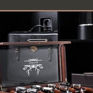 a wooden watch box with a lid, displaying several watches inside. The watch box has a personalized and personalized wooden design, and it is accompanied by a button for shopping. The background of the image is dark, which emphasizes the watch box and its contents.