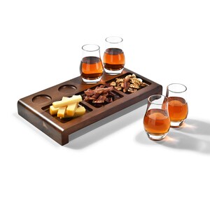 A wooden tray with various snacks and drinks, including cheese, nuts, and glasses of what appears to be a dark liquid, possibly wine or liquor.