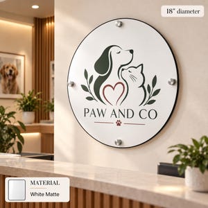 a round sign with a logo of a dog and a cat, along with the text "PAW AND CO" and a heart symbol. The sign is mounted on a wall, and there are some plants and a counter visible in the background.