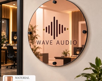 Puede incluir: Un espejo circular de color oro rosa con un diámetro de 61 cm, que presenta un gráfico negro de ondas sonoras verticales y el texto "WAVE AUDIO" en el centro. El espejo está sujeto con cuatro piezas de montaje circulares negras en los bordes.