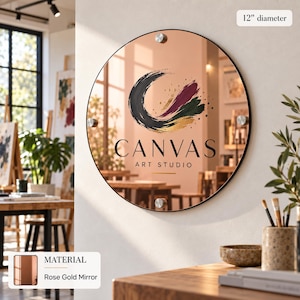a round mirror with the text "CANVAS ART STUDIO" on it, mounted on a wall in an art studio.