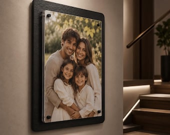May include: A rectangular wall-mounted photo frame featuring a black textured border and a clear acrylic front panel secured with four black corner standoffs. The frame displays a portrait of two adults and two children smiling together outdoors.