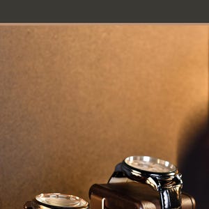 a compact wood organizer tray with two watches displayed on it, placed on a wooden surface.