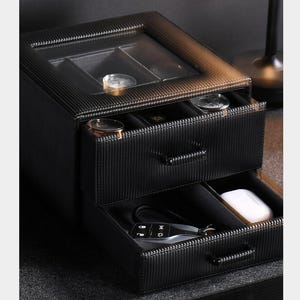 a black drawer organizer with a drawer and a compartment, sitting on a desk.