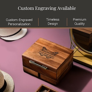 a wooden box with a butterfly design, placed on a pink surface. The box has a handle on the front and appears to be a custom-engraved wooden box.
