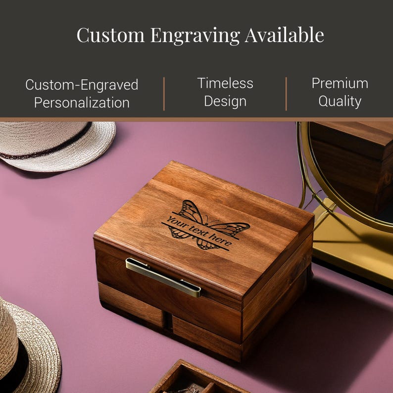 a wooden box with a butterfly design, placed on a pink surface. The box has a handle on the front and appears to be a custom-engraved wooden box.