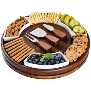 May include: A wooden serving tray with white ceramic bowls filled with almonds, crackers, blueberries, and cookies. The tray also includes cheese knives and a fork with wooden handles, and sliced green fruit.