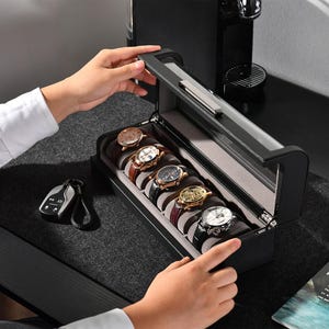 a person opening a watch box on a desk