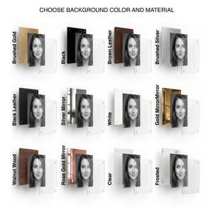 May include: A grid of twelve display options labeled CHOOSE BACKGROUND COLOR AND MATERIAL, featuring a portrait photo layered between a colored or textured backing plate and a clear acrylic front panel with corner mounting hardware.