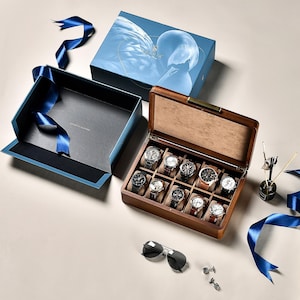 Peut inclure: Une boîte de rangement en bois pour dix montres, accompagnée d'un coffret cadeau bleu illustré d'un cygne, d'un ruban bleu, d'une paire de lunettes de soleil teintées foncées et de deux petits boutons de manchette en métal.