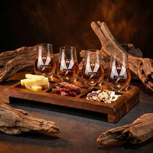 A wooden tray displaying four glasses filled with amber-colored liquid, likely whiskey, alongside various food items such as cheese, bacon, and nuts.