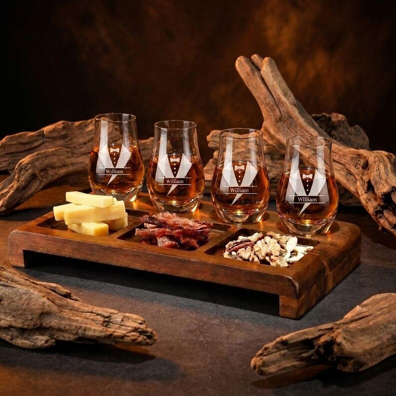 A wooden tray displaying four glasses filled with amber-colored liquid, likely whiskey, alongside various food items such as cheese, bacon, and nuts.