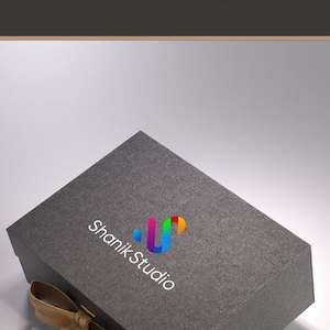 The image is an advertisement for Shank Studio, featuring a gray gift box with a gold ribbon and the Shank Studio logo.