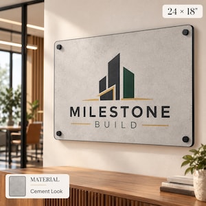 a sign for "Milestone Build" mounted on a wall, with a wooden desk and a plant in the foreground.